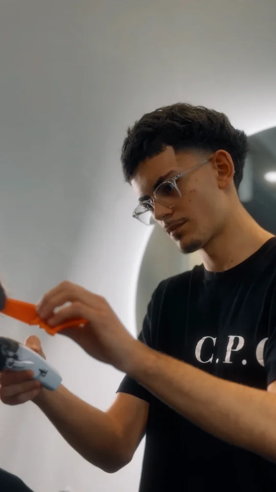 Tom au travail, le peigne et la tondeuse à la main, dans la vidéo de sa coupe